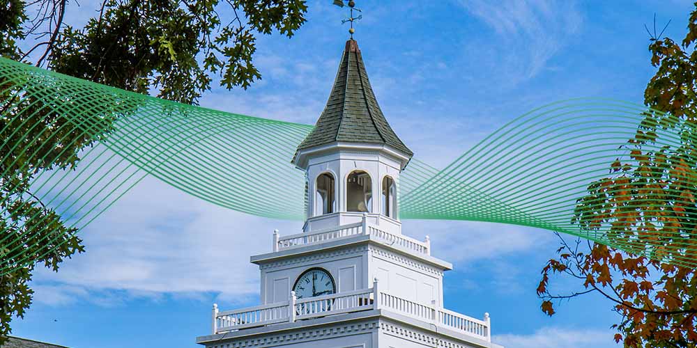 Clock tower with a pointed roof and bell.
